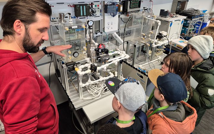 Kinder des Workshops der Kinderuni schauen sich eine Studienarbeit an